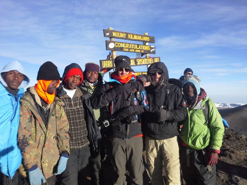 Guests and guides at the Uhuru Peak summit sign