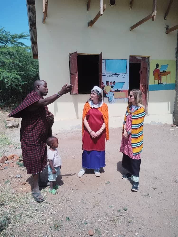 A Maasai elder and child with guests at a local school